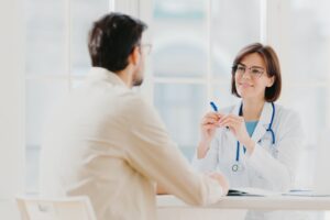 Skilled therapist in white uniform talks with patient